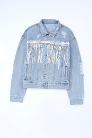 Medium wash denim trucker jacket with distressed details and white fringe accents.