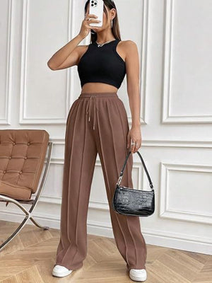 Brown pleated wide-leg lounge trousers with drawstring waist and front seams.