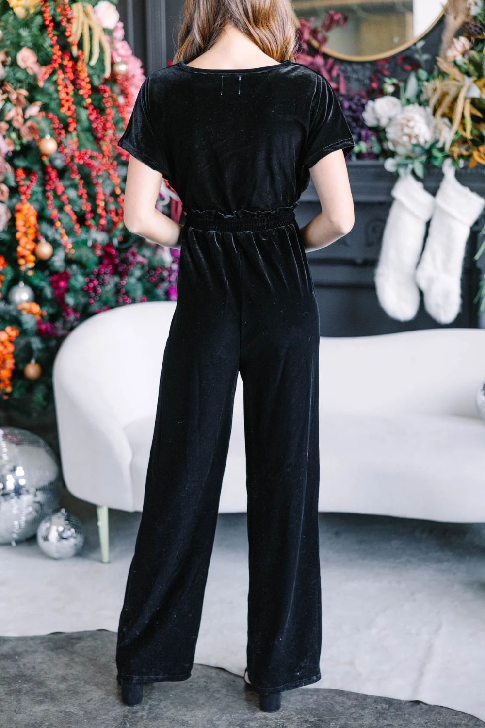 Black velvet wrap bodice jumpsuit with elastic waist and wide legs.
