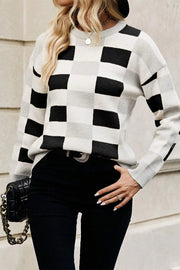 Black and white checkerboard knit pullover sweater with crew neck and long sleeves.