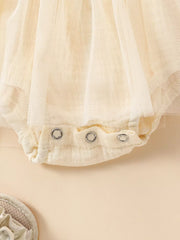 Apricot smocked baby bodysuit with snap closure and tulle overlay detail.