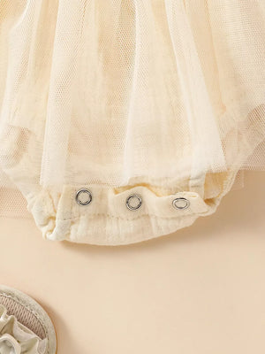 Apricot smocked baby bodysuit with snap closure and tulle overlay detail.