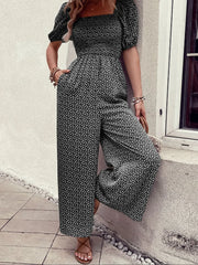 Black floral smocked bodice jumpsuit with wide legs and puff sleeves.