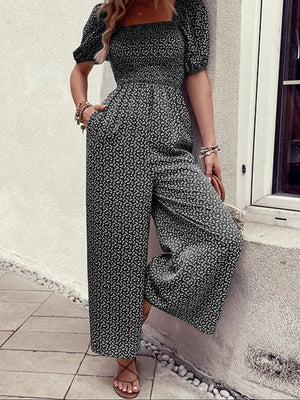 Black floral smocked bodice jumpsuit with wide legs and puff sleeves.