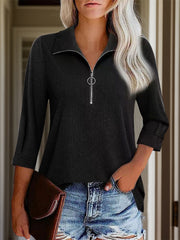 Black textured zip-front polo top with a ring zipper pull and cuffed sleeves.