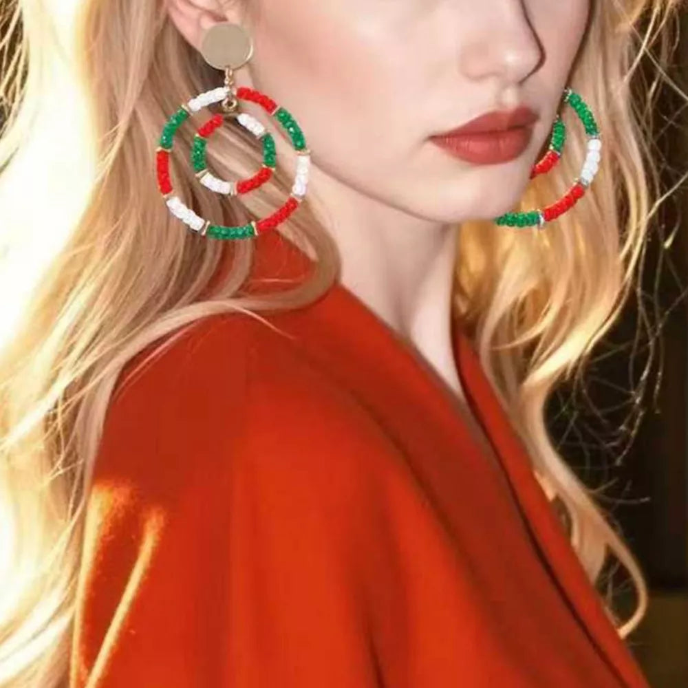 Festive beaded hoop earrings in red, white, and green, with a spiral design.