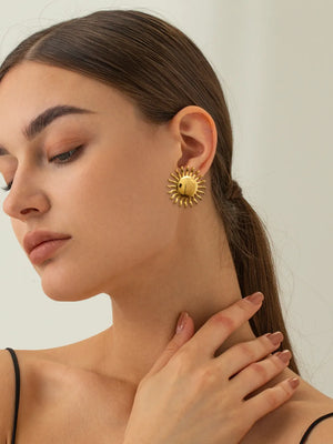 Gold sun stud earrings with sculpted rays and a ladybug detail.