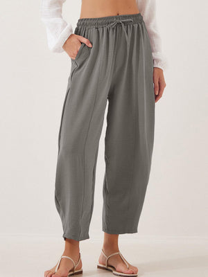Gray balloon trousers with drawstring waist and sculpted seamline detail.