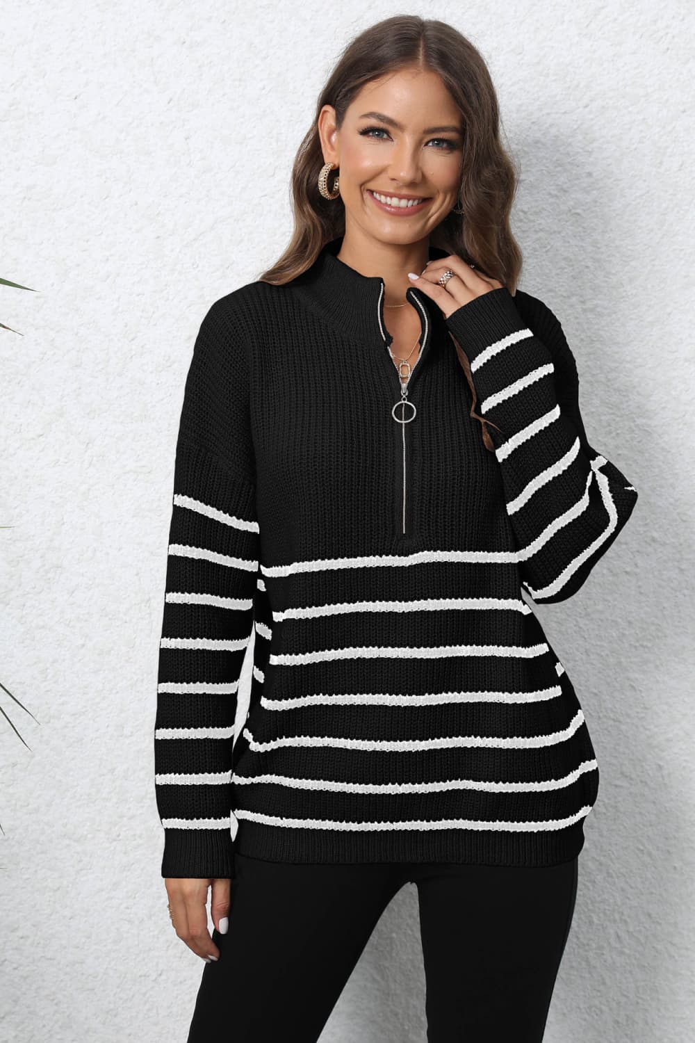 Black ribbed knit quarter-zip sweater with white horizontal stripes and a silver zipper detail.