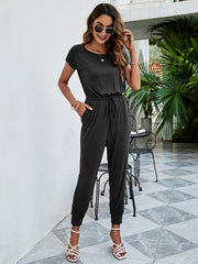 Black jersey jumpsuit with short sleeves, drawstring waist, and cuffed ankles.