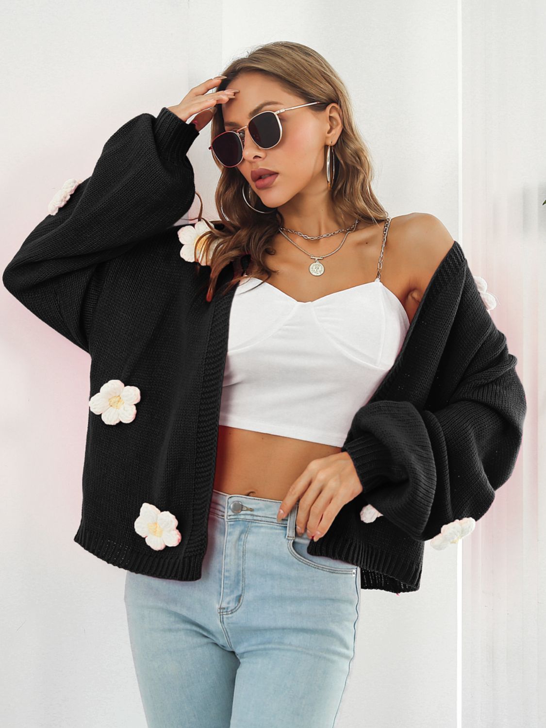 Black knit cardigan with floral appliqué and balloon sleeves.