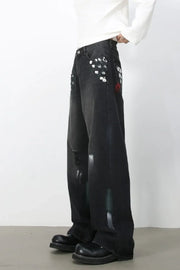 Dark wide-leg jeans with painterly brushstroke details and distressed accents.