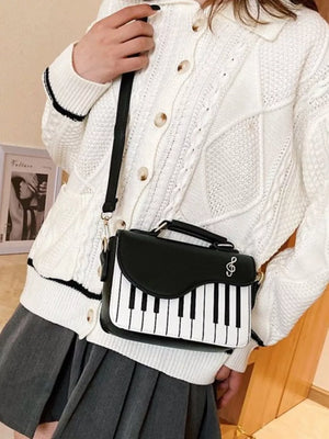 Black and white piano key crossbody bag with a treble clef detail.