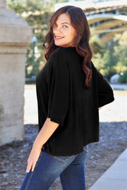 Black boxy dolman crop t-shirt with short sleeves and a relaxed fit, styled with jeans.