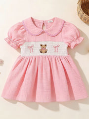 Pink baby dress with smocked bodice, teddy bear embroidery, Peter Pan collar, and puff sleeves.