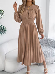 Ruffled smocked waist midi dress in khaki with long sleeves and a pleated skirt.