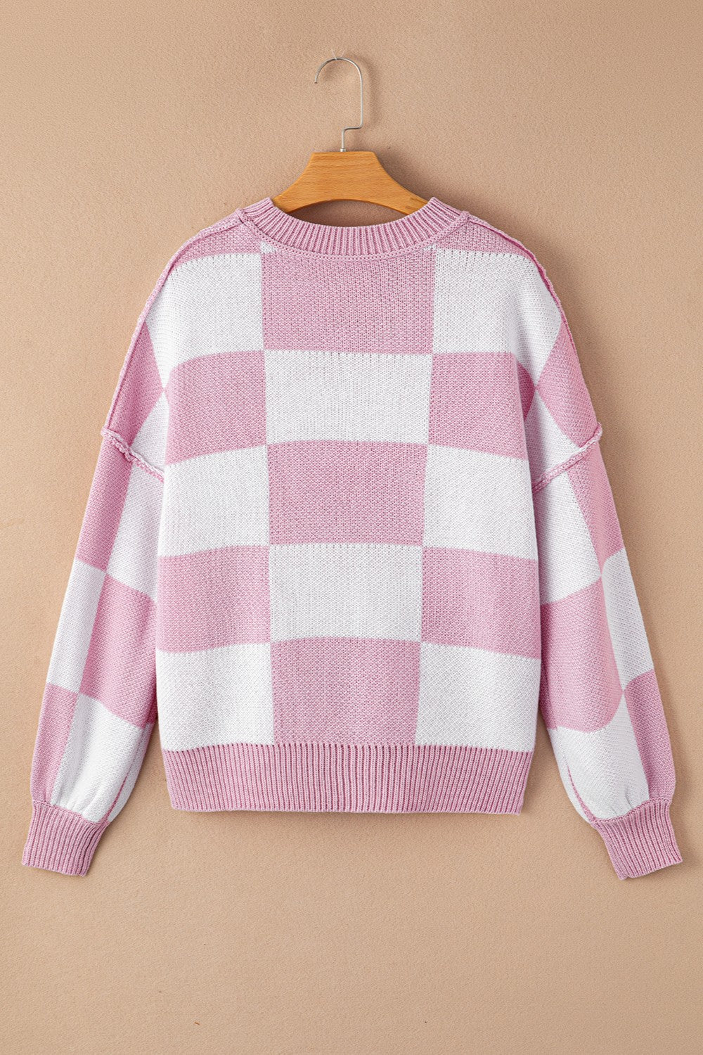 Checkerboard knit crewneck sweater in pink and white with balloon sleeves.
