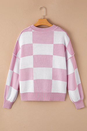 Checkerboard knit crewneck sweater in pink and white with balloon sleeves.