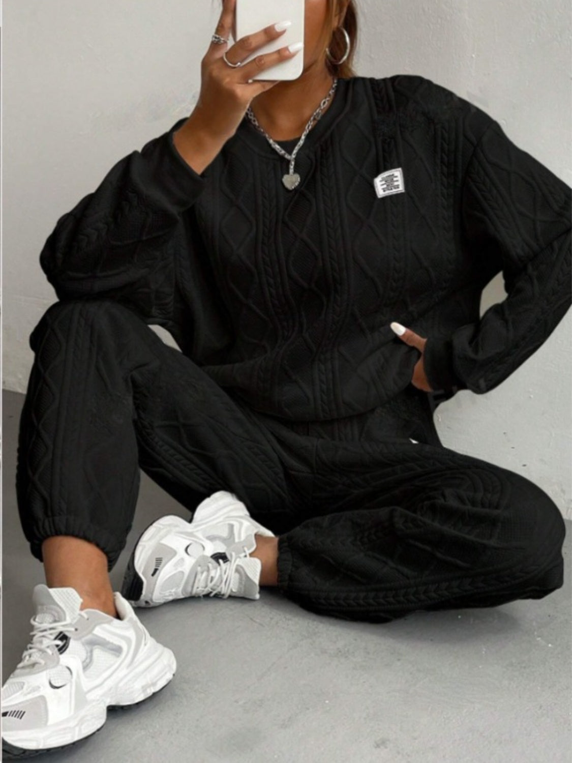 Black cable knit loungewear set with crew neck sweater and cuffed pants.