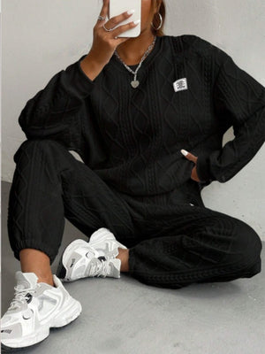 Black cable knit loungewear set with crew neck sweater and cuffed pants.