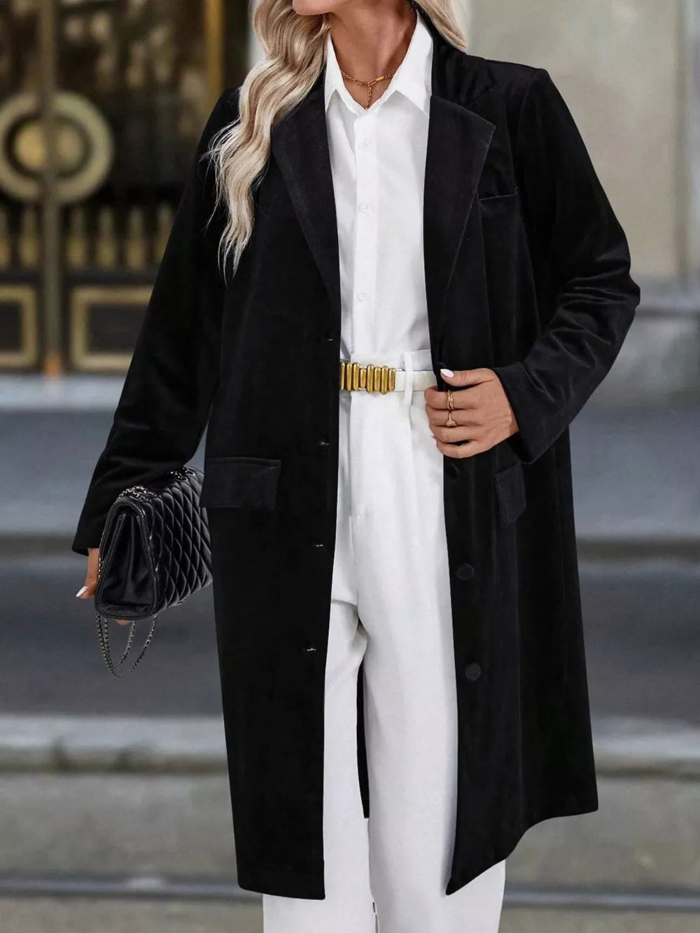 Black longline trench coat with lapel collar, buttoned front, and flap pockets.