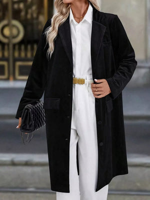 Black longline trench coat with lapel collar, buttoned front, and flap pockets.