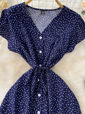 Dark blue polka dot maxi dress with V-neck, short sleeves, button front, and tie belt.