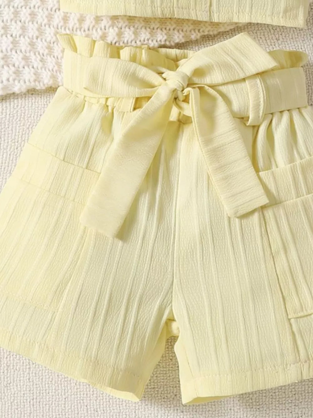 Light yellow ruffled ribbed toddler shorts with paperbag waist and tie detail.
