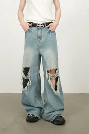 Distressed wide-leg denim jeans in medium wash with fraying and ripped knees.