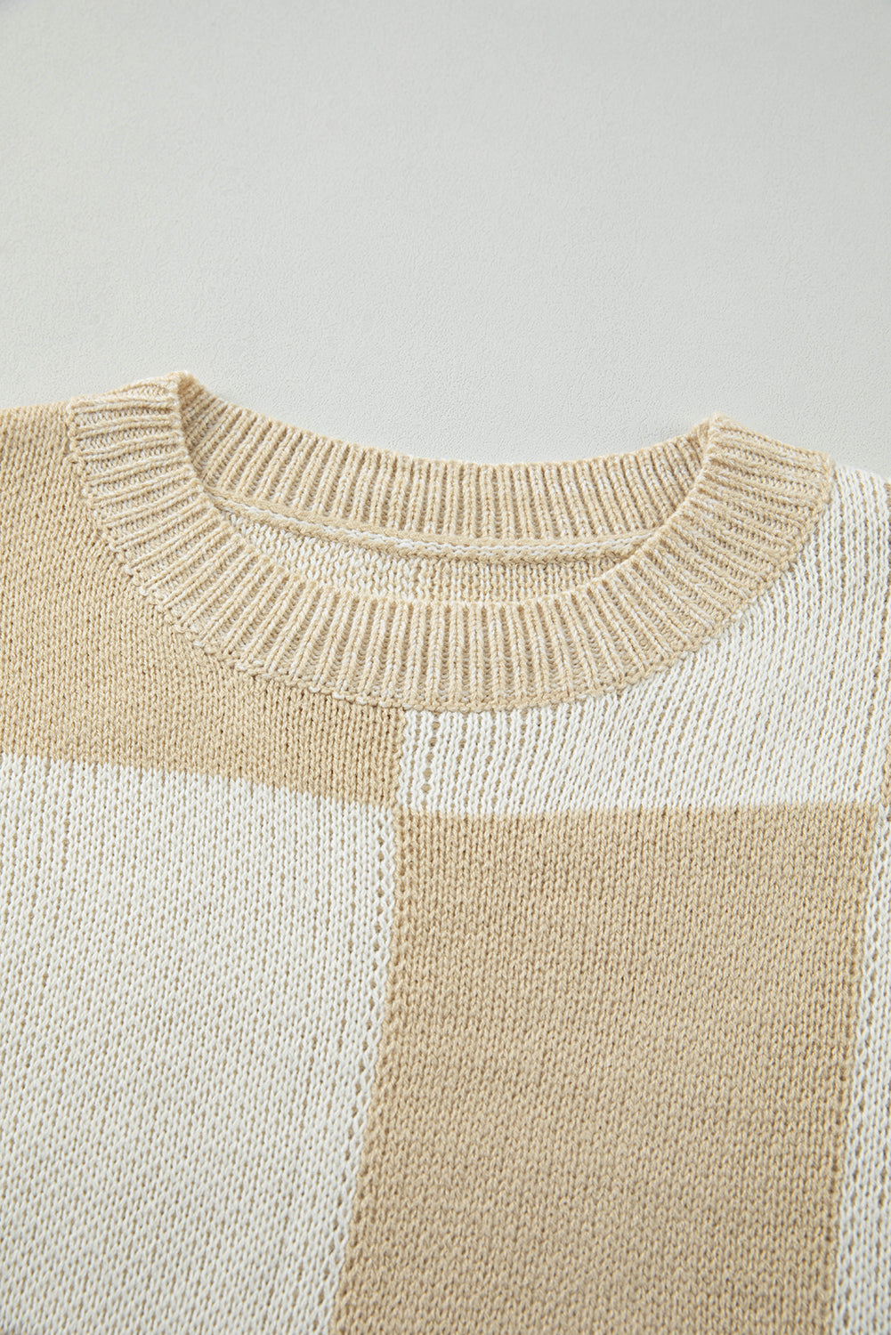 Beige and cream colorblock checkerboard knit sweater with crew neck.
