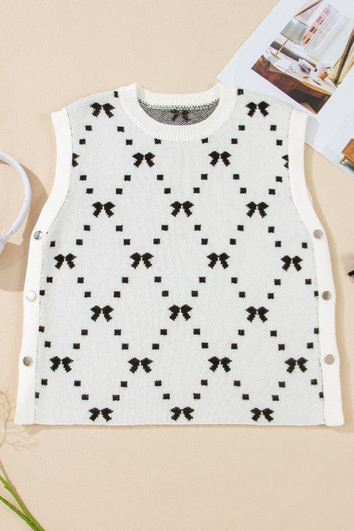White knit tank sweater with black diamond bow pattern and snap sides.