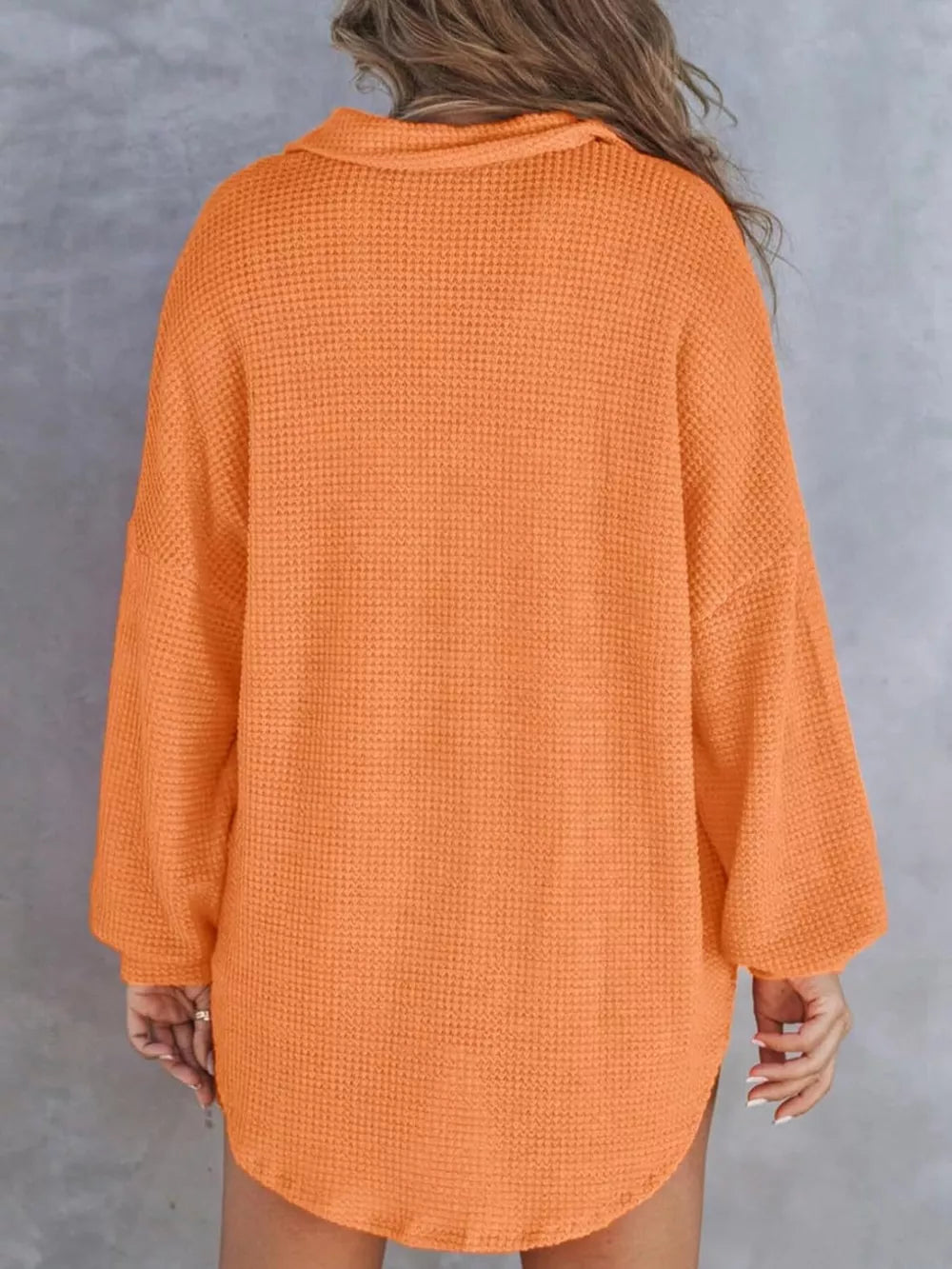 Orange waffle-knit henley tee with pocket, long sleeves and collared neckline.