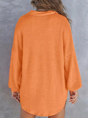 Orange waffle-knit henley tee with pocket, long sleeves and collared neckline.