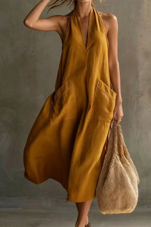 Mustard halter midi dress with deep V-neck, pockets, and flowing skirt.