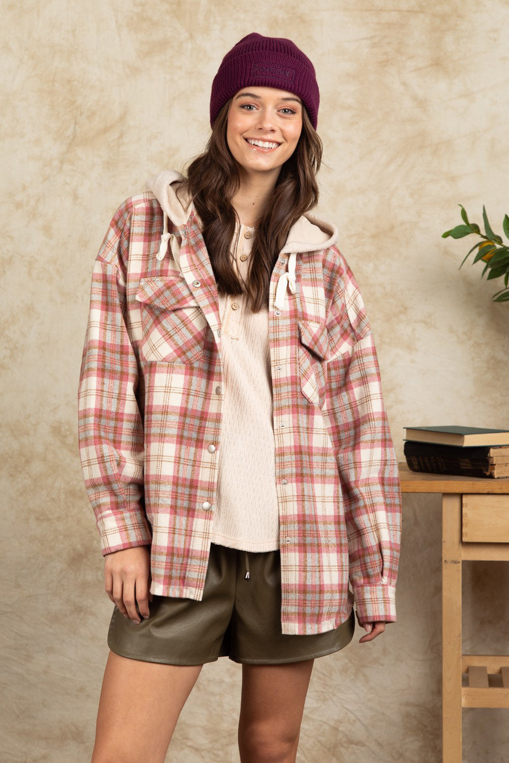 Cozy plaid shacket with sherpa hood in Dusty Pink, featuring buttoned pockets and a relaxed fit.