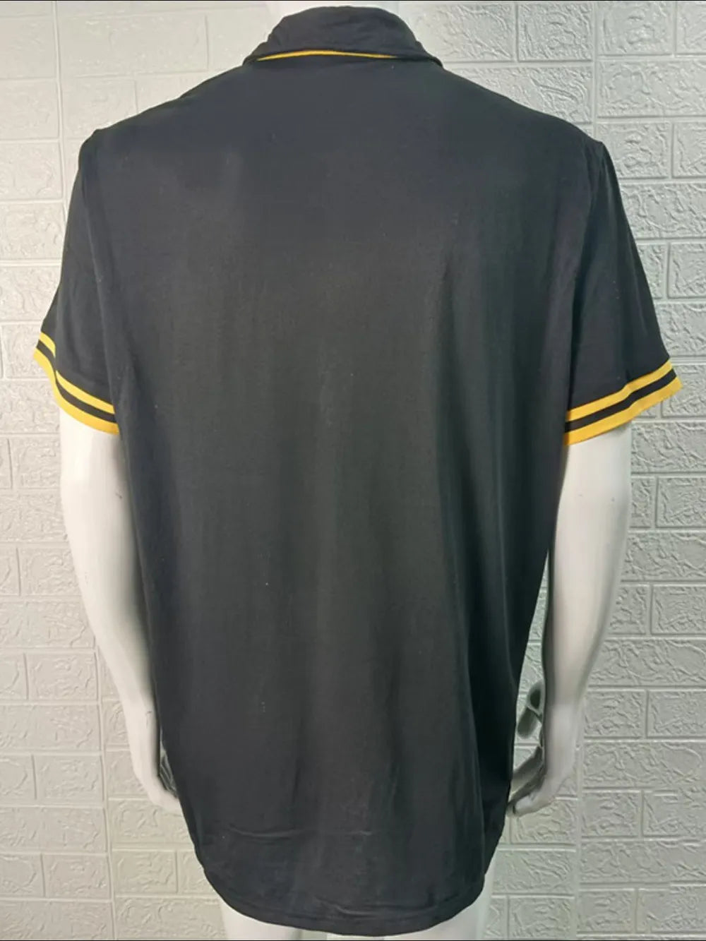 Black polo shirt with yellow trim on collar and sleeves.