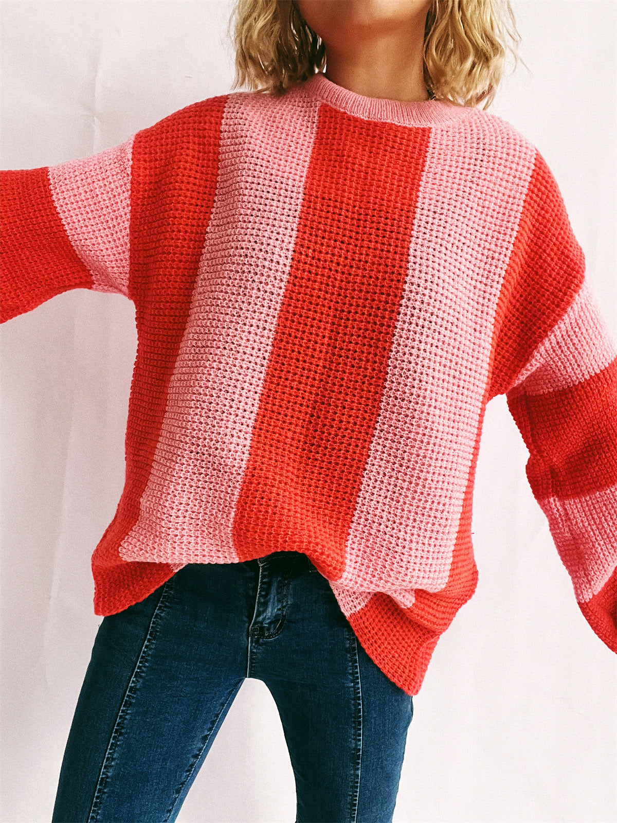Vertical stripe waffle knit sweater in orange-red and pink, crew neck, long sleeves.