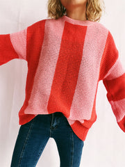 Vertical stripe waffle knit sweater in orange-red and pink, crew neck, long sleeves.