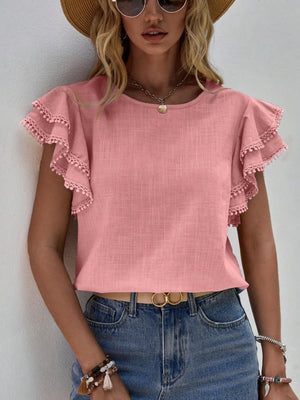 Dusty pink blouse with ruffle sleeves trimmed in pom-poms.