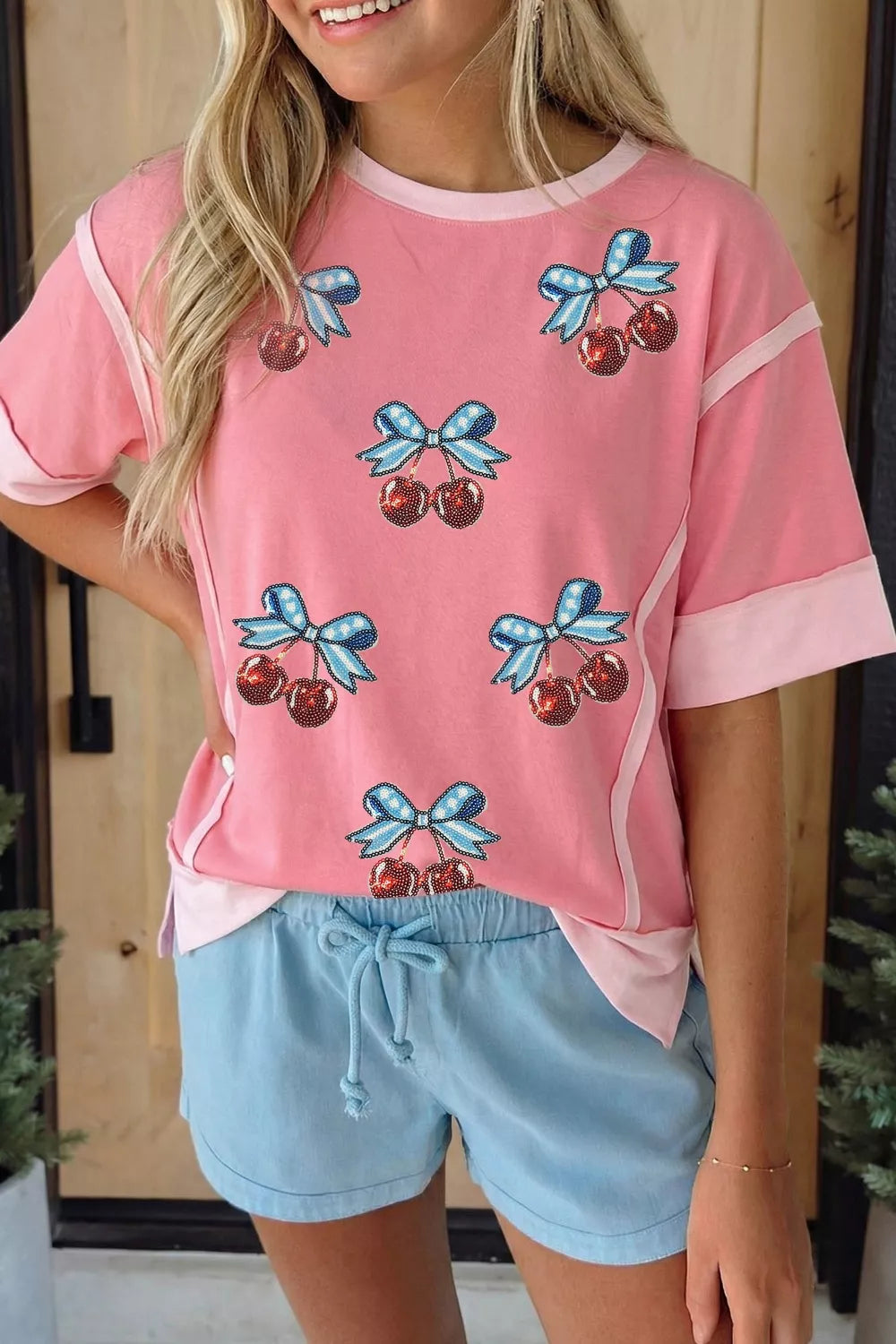 Pink polyester t-shirt with sequin cherry and bow graphic, contrast trim, short sleeves.