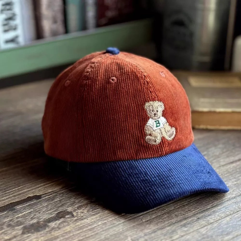 Terracotta corduroy baseball cap with blue brim and embroidered bear detail