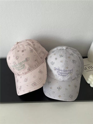 Embroidered floral baseball caps in pink and light gray with "Weekend Calling Company" text.