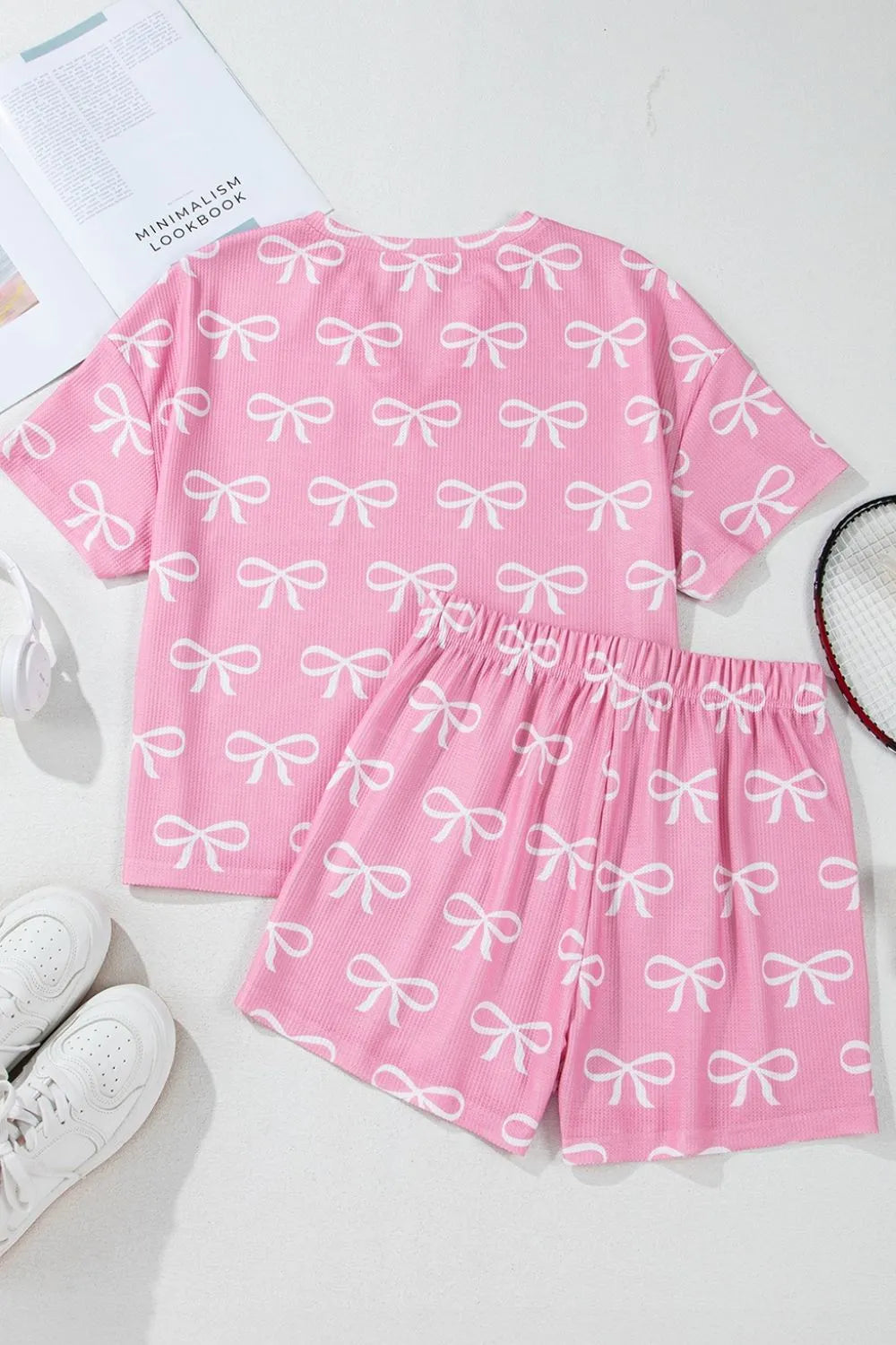 Pink ribbed lounge set with white bow print, featuring a short sleeve top and shorts.