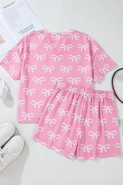 Pink ribbed lounge set with white bow print, featuring a short sleeve top and shorts.