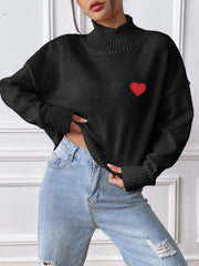Black cropped turtleneck knit sweater with embroidered red heart detail and ribbed cuffs.