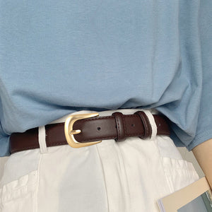 Brown leather belt with gold buckle, adjustable, worn with white pants.