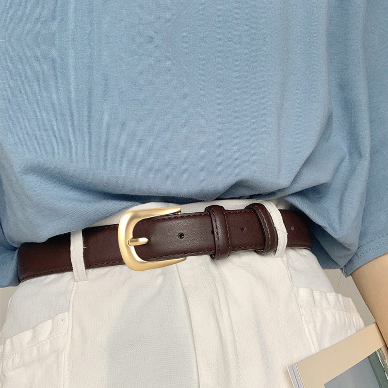Brown leather belt with gold buckle, adjustable, worn with white pants.