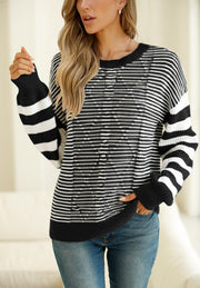 Black and white geometric stripe knit sweater with crew neck and long sleeves.