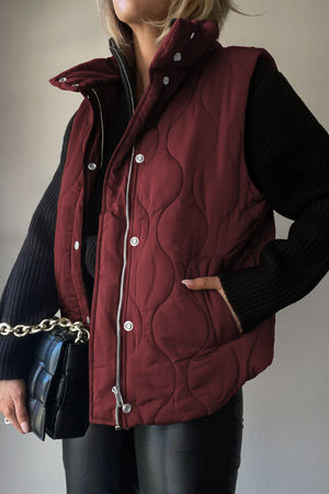 Wine quilted stand-collar utility gilet with snap and zip closure.