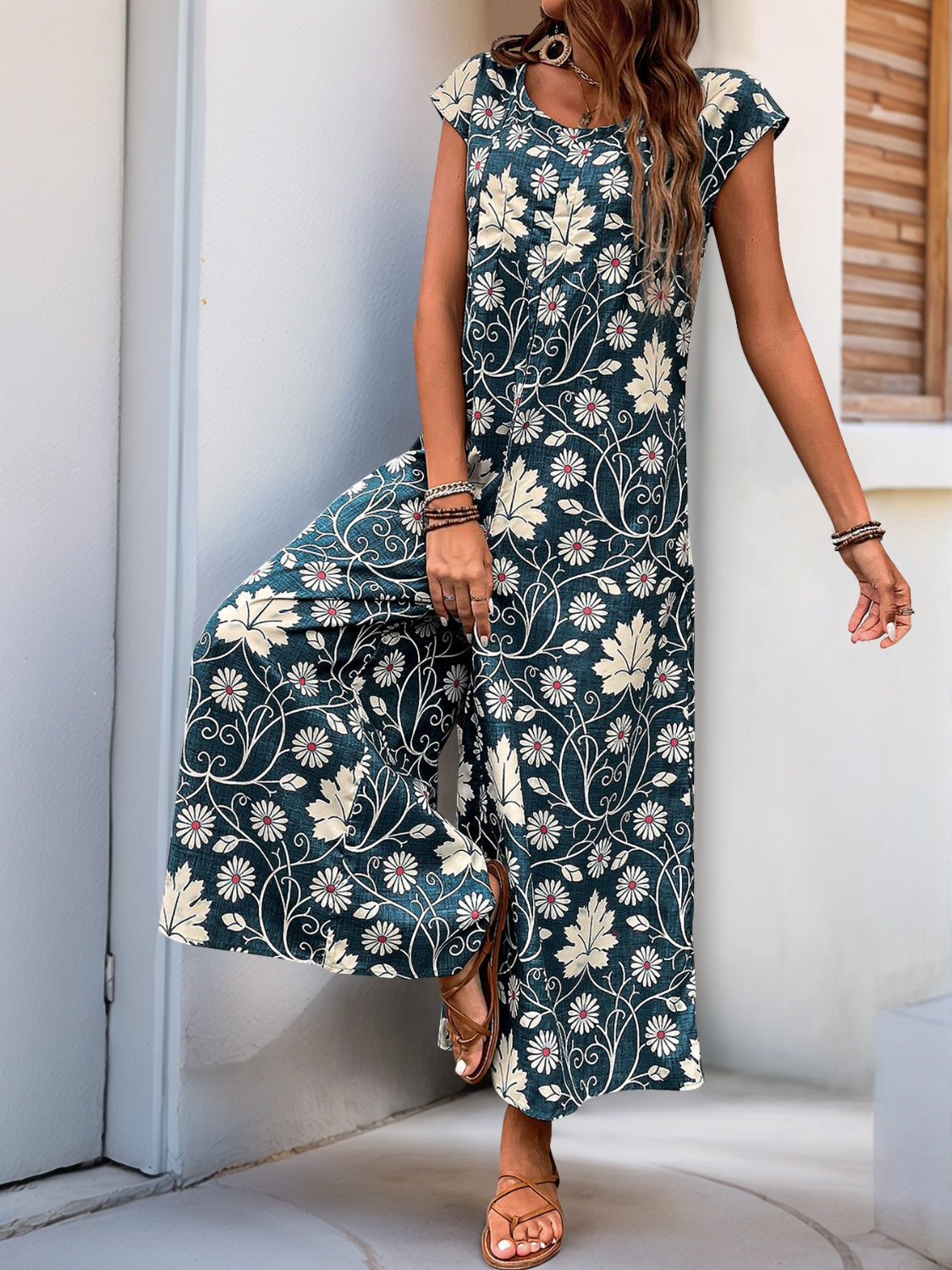 Botanical print culotte jumpsuit in dark green with short sleeves and wide legs.